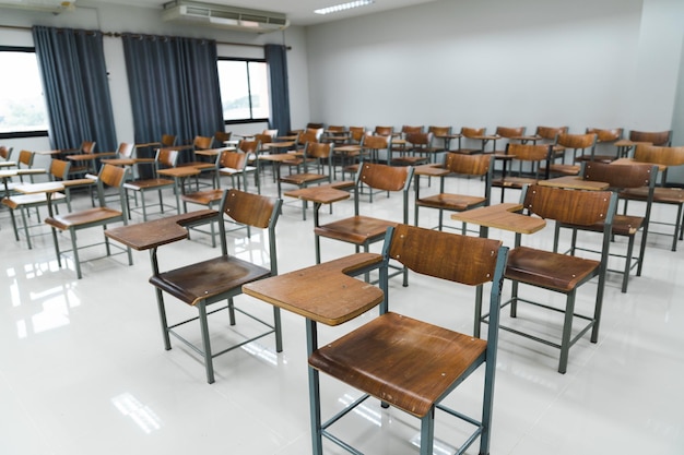 Foto schulklassenzimmer mit vielen holzstühlen, die ohne schüler in reihen angeordnet sind