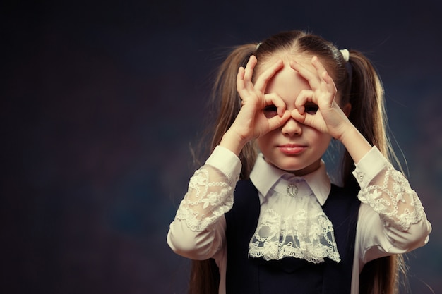 Schulmädchen bauen Brille auf Gesicht mit Handaffen. Farbton