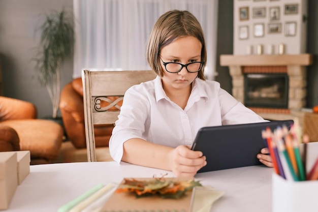 Schulmädchen beschäftigt sich mit Homeschooling und sieht sich zu Hause Online-Lernvorträge auf dem Laptop an