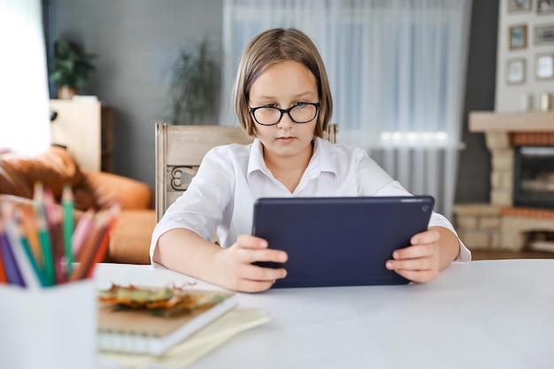 Schulmädchen beschäftigt sich mit Homeschooling und sieht sich zu Hause Online-Lernvorträge auf dem Laptop an