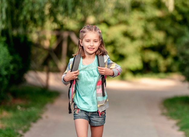 Schulmädchen, das durch Park durch Schule geht