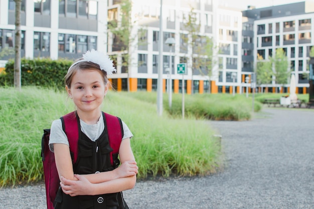 Schulmädchen des kleinen Mädchens steht nahe der Schule