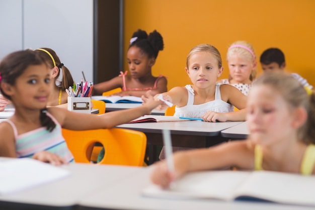 Schulmädchen gibt ihren Freunden im Klassenzimmer Scheiße