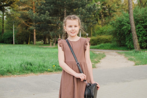 Schulmädchen in einem braunen Kleid im Park