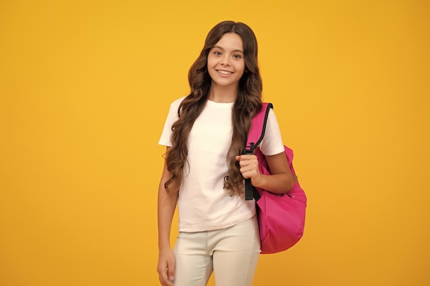 Schulmädchen in Schuluniform mit Schultasche Schulkind Teenager-Student halten Rucksack auf gelb isoliertem Hintergrund