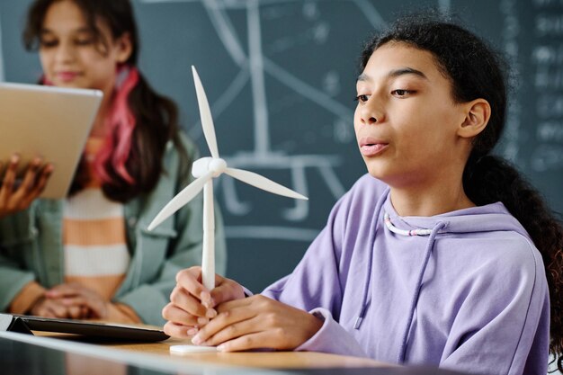 Schulmädchen lernt am Tisch im Klassenzimmer die Arbeit einer Windmühle