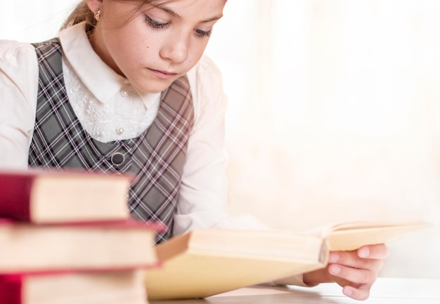 Schulmädchen liest ein Buch in der Nähe in der Bibliothek