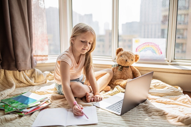 Schulmädchen macht Hausaufgaben während des Online-Unterrichts zu Hause