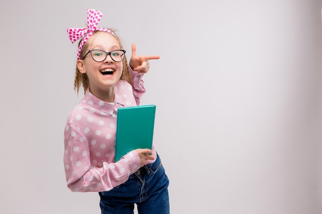 Schulmädchen mit Brille mit einem Buch lächelnd