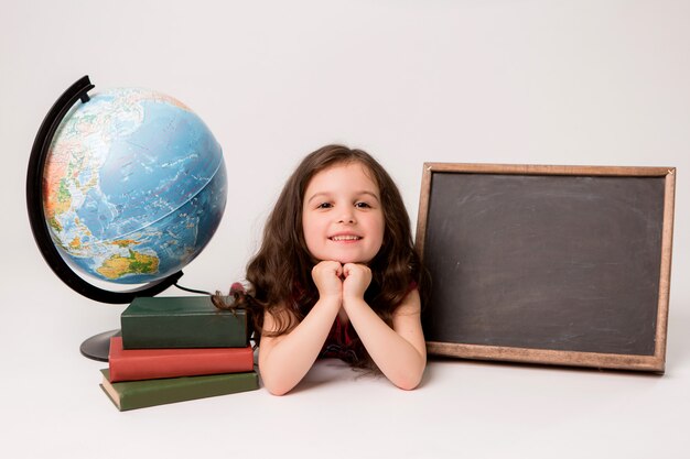 Schulmädchen mit Büchern, einem Globus und einem leeren Reißbrett