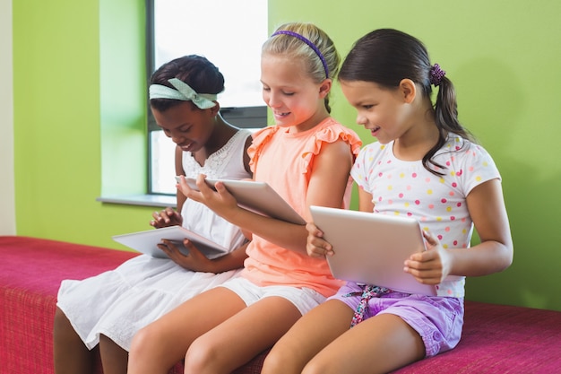 Schulmädchen mit digitalem Tablet in der Bibliothek