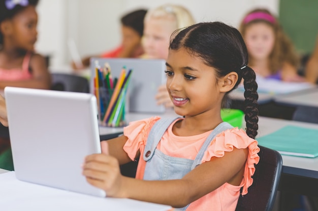 Schulmädchen mit digitaler Tablette im Klassenzimmer