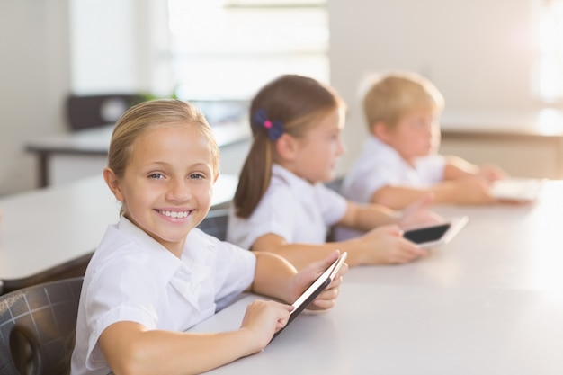 Schulmädchen mit digitaler Tablette im Klassenzimmer