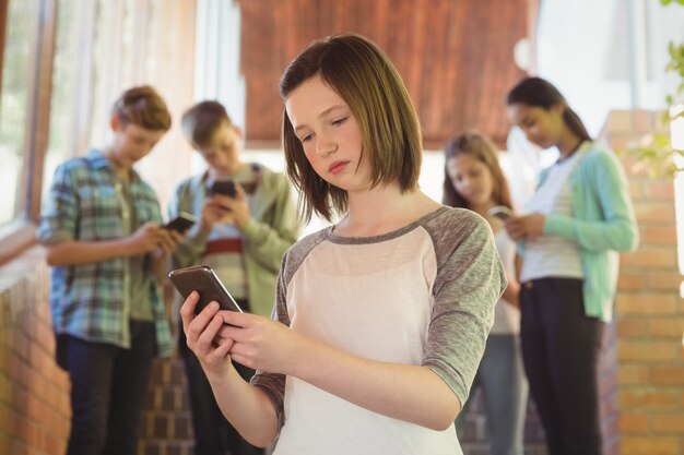 Schulmädchen mit Handy im Korridor