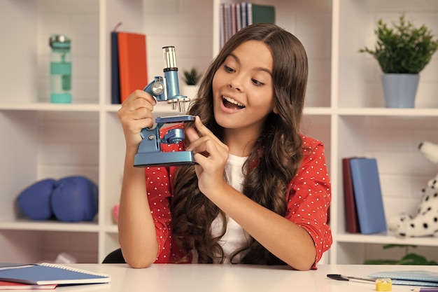 Schulmädchen mit Mikroskop für Schulbildung Klassenzimmer Aufgeregtes Gesicht fröhliche Emotionen Teenager
