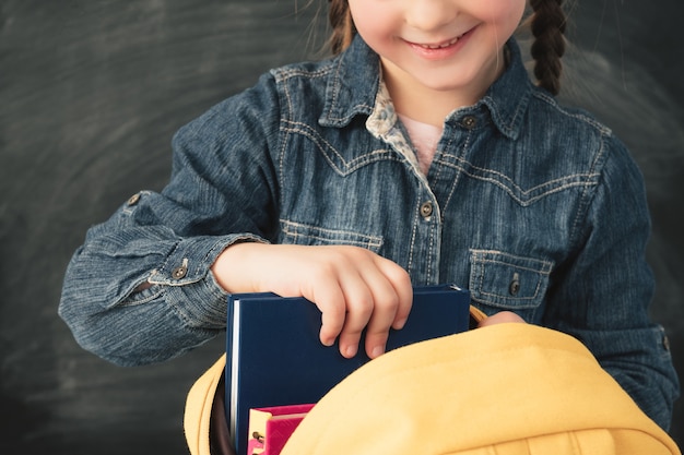 Foto schulmädchen mit zöpfen, die gelben rücken mit büchern tragen