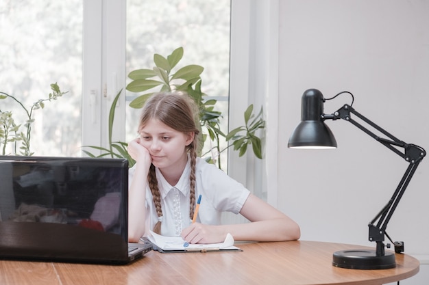 Schulmädchen-Selbstisolation mit Laptop für seine Hausaufgaben. Mädchen, das während der Sperrung von Covid 19 mit digitalen Tablets nach Informationen im Internet sucht. Soziale Distanz, E-Learning-Online-Bildung