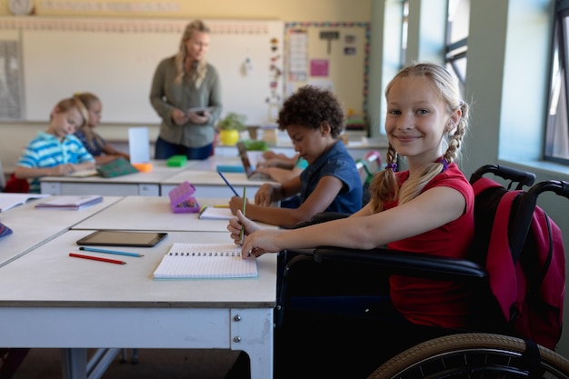 Schulmädchen sitzt im Rollstuhl in einem Grundschulklassenzimmer