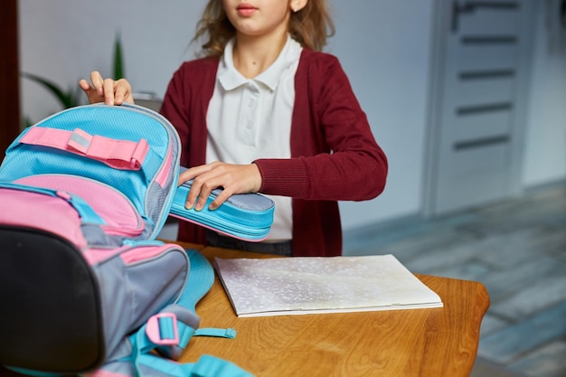 Schulmädchen steckt Bücher und Notizen in den Rucksack zu Hause. Schülerin bereitet Personal auf Bildung vor