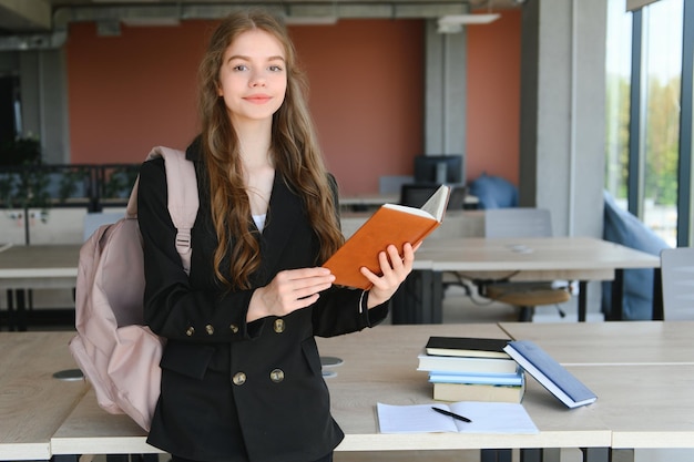 Schulmädchen steht mit Büchern und Rucksack in der Schule