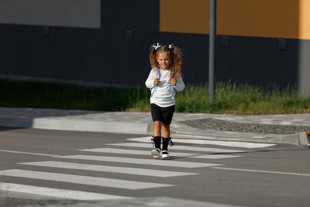 Schulmädchen überquert die Straße an einem Fußgängerüberweg