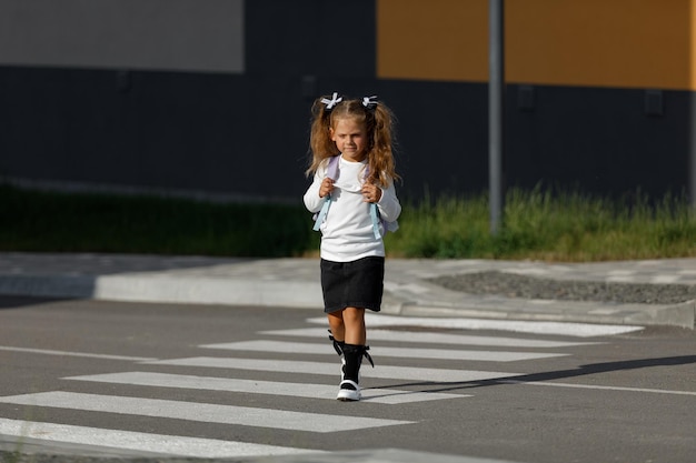 Schulmädchen überquert die Straße an einem Fußgängerüberweg