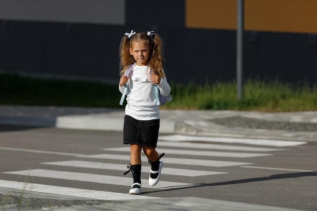 Schulmädchen überquert die Straße an einem Fußgängerüberweg