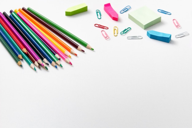 Schulmaterial. Farbige Bleistifte, farbige Büroklammern auf Weiß. Kopieren Sie Platz.