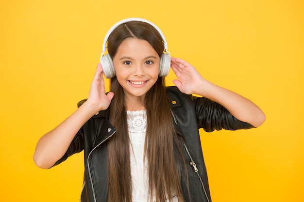 Schulradio dj. Lady DJ langes Haar. glückliches Lächeln. Hipster-Mädchen im urbanen Stil. Lifestyle-Konzept. Biker-Kind im Headset. kleines Mädchen in Lederjacke. Herbstmode-Stil. Kind hört Rockmusik.