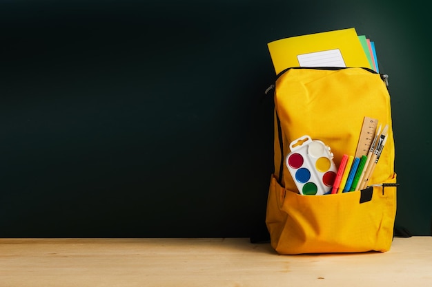 Schulrucksack mit buntem Schulmaterial auf dem Tisch