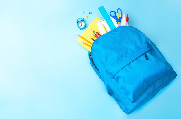 Schultasche Rucksack mit Schulgeräten auf blauem Hintergrund Kopierraum für Text