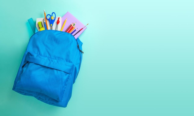 Schultasche Rucksack mit Schulgeräten auf blauem Hintergrund Kopierraum für Text