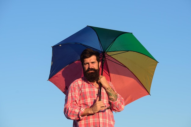 Schulterporträt eines schwulen homosexuellen Mannes mit Regenbogenregenschirm in Regenbogenfarben lgbt...