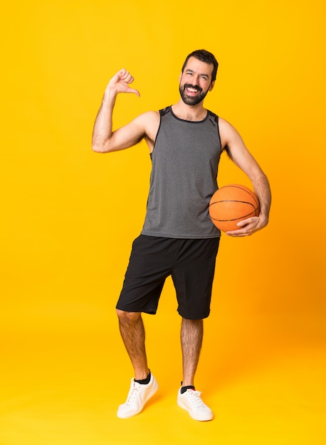 Schuss in voller Länge des Mannes über lokalisiertem gelbem spielendem Basketball und stolz auf sich