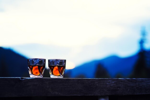 Schuss Whisky bei Sonnenuntergang dramatischen Himmel auf Berglandschaft Hintergrund