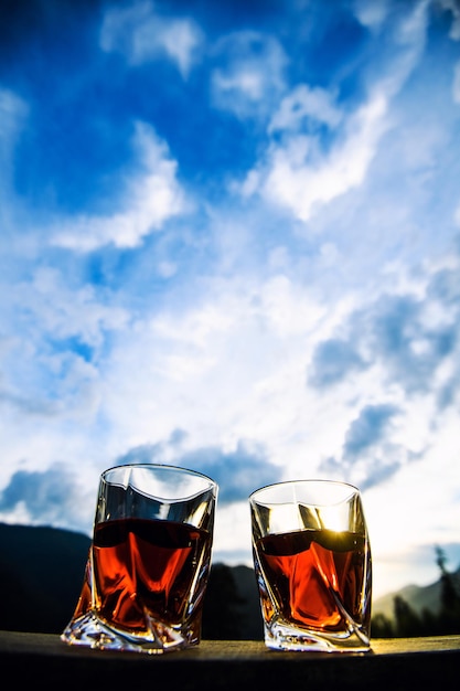 Schuss Whisky bei Sonnenuntergang dramatischen Himmel auf Berglandschaft Hintergrund