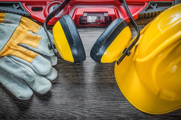 Schutzhandschuhe auf Bauebene Schutzhelm-Ohrenschützer auf Holzbrett