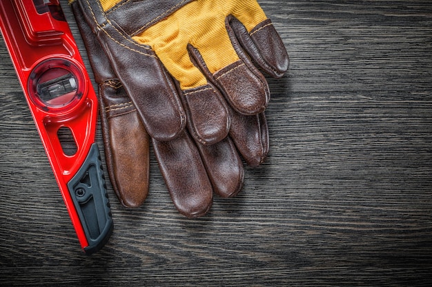 Schutzhandschuhe aus Leder auf Bauebene auf Holzbrett