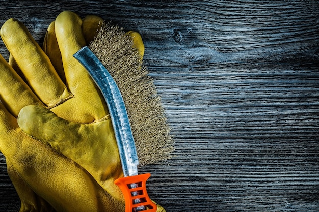 Schutzhandschuhe aus Leder mit Kratzdrahtbürste auf Vintage-Holzbrett