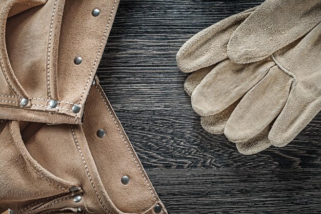 Schutzhandschuhe aus Leder mit Werkzeuggürtel auf schwarzem Brett