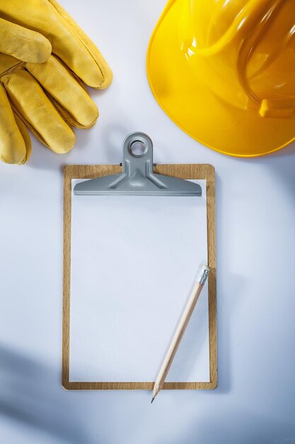 Schutzhandschuhe aus Leder Schutzhelm Klemmbrett Bleistift auf weißem Hintergrund