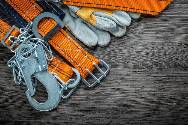 Schutzhandschuhe Baukörpergürtel auf Holzbrett Draufsicht.