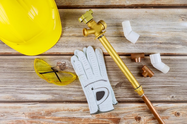 Schutzhandschuhe für harte Arbeit an gelbem Schutzhelm, Kupferrohren und Schutzbrille