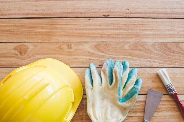 Schutzhelm, Handschuhe, Kelle und Pinsel auf Holzbrett von oben