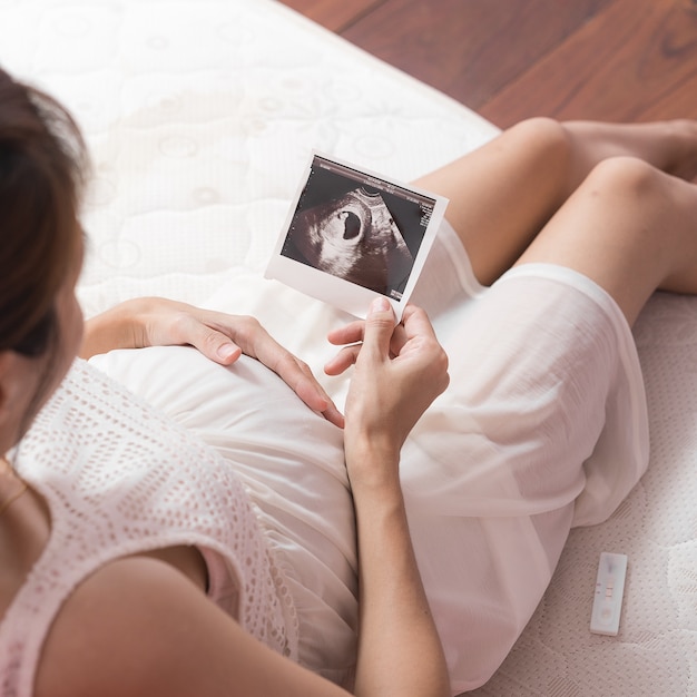 Foto schwangere asiatische frau, die ultraschallscan des schätzchens betrachtet