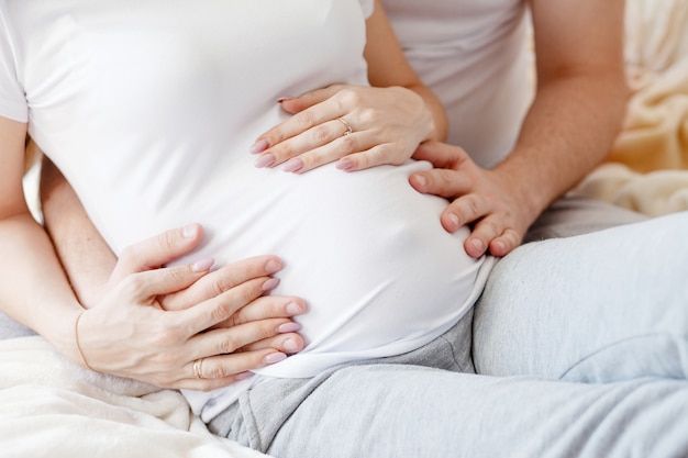 Schwangere Bauch mit Händen von Mutter und Vater zusammen. Baby erwartet. Schwangere Frau. Schwangerschaft.