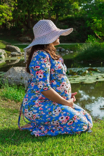 Schwangere Frau am Seeufer, während sie ihren Bauch im Freien Mutterschaftskonzept berührt