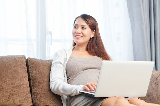 Schwangere Frau arbeitet am Laptop