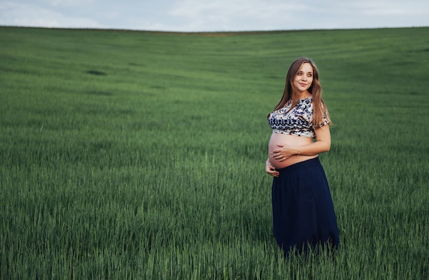 Schwangere Frau auf dem Gebiet des grünen Weizens