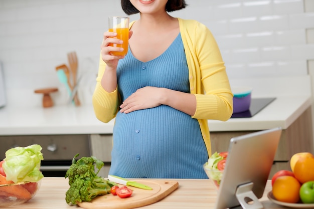 Schwangere Frau auf Küche, die gesunden Fruchtsaft trinkt